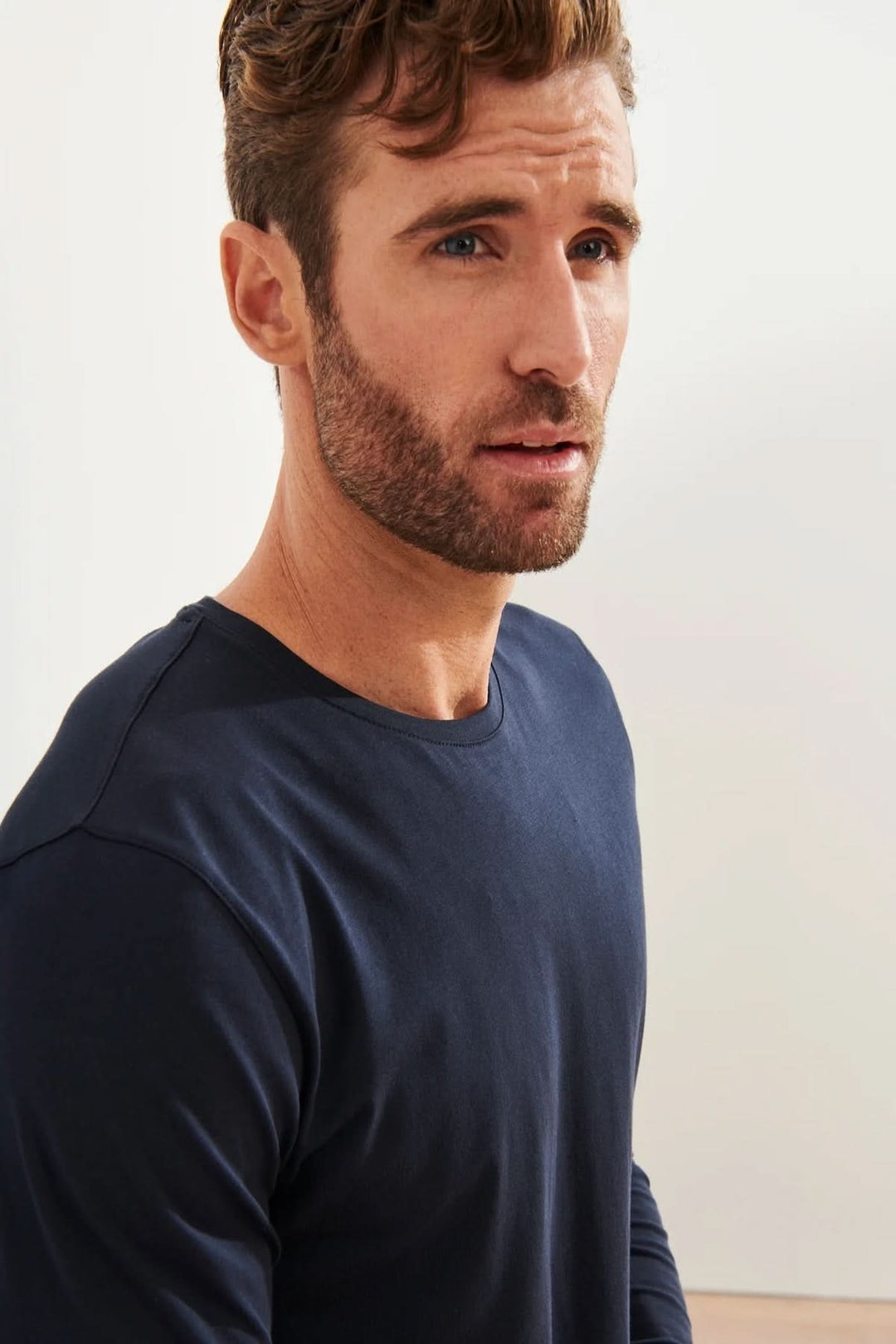 Homme portant un t-shirt à manches longues, col rond en coton Pima, couleur navy, avec un fond neutre.