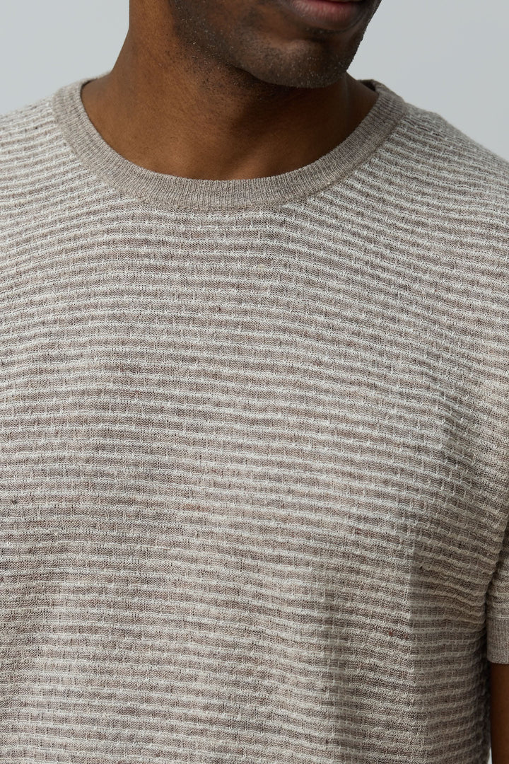 Homme portant un T-shirt texturé en lin et soie à manches courtes et col rond, allure moderne et tissu léger.