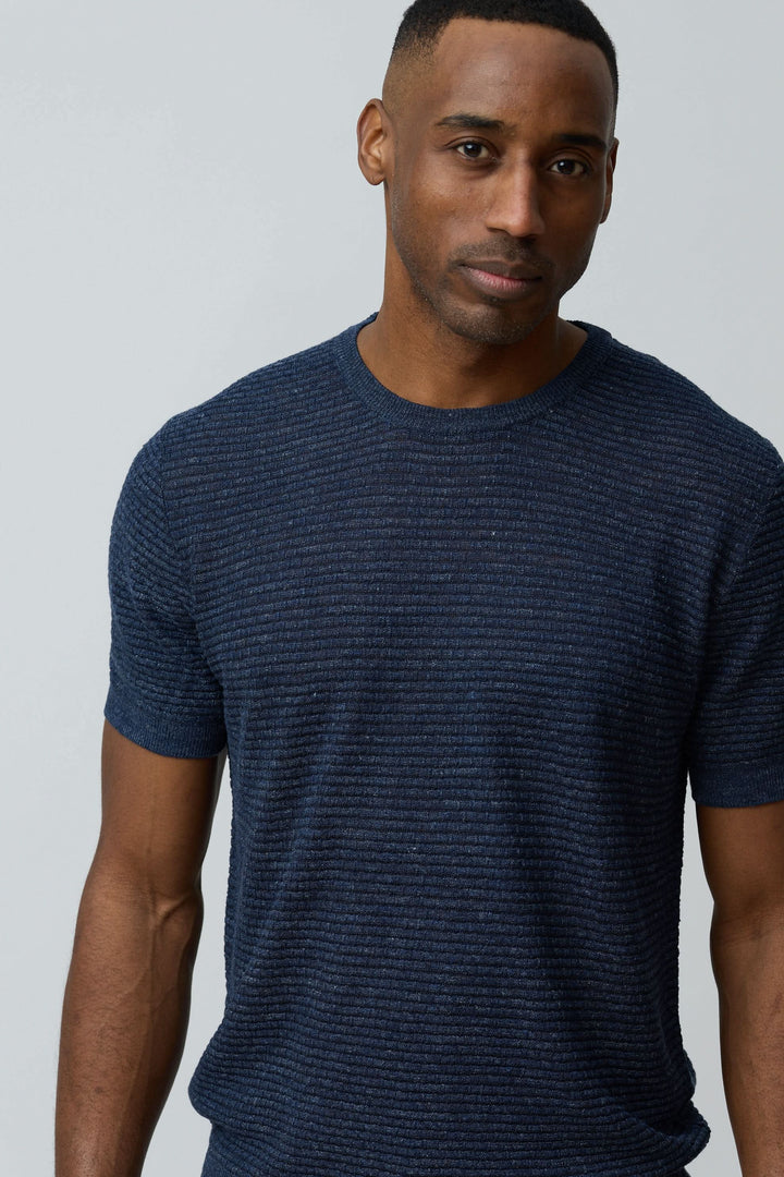 Homme portant un T-shirt texturé en lin et soie bleu, coupe ajustée.