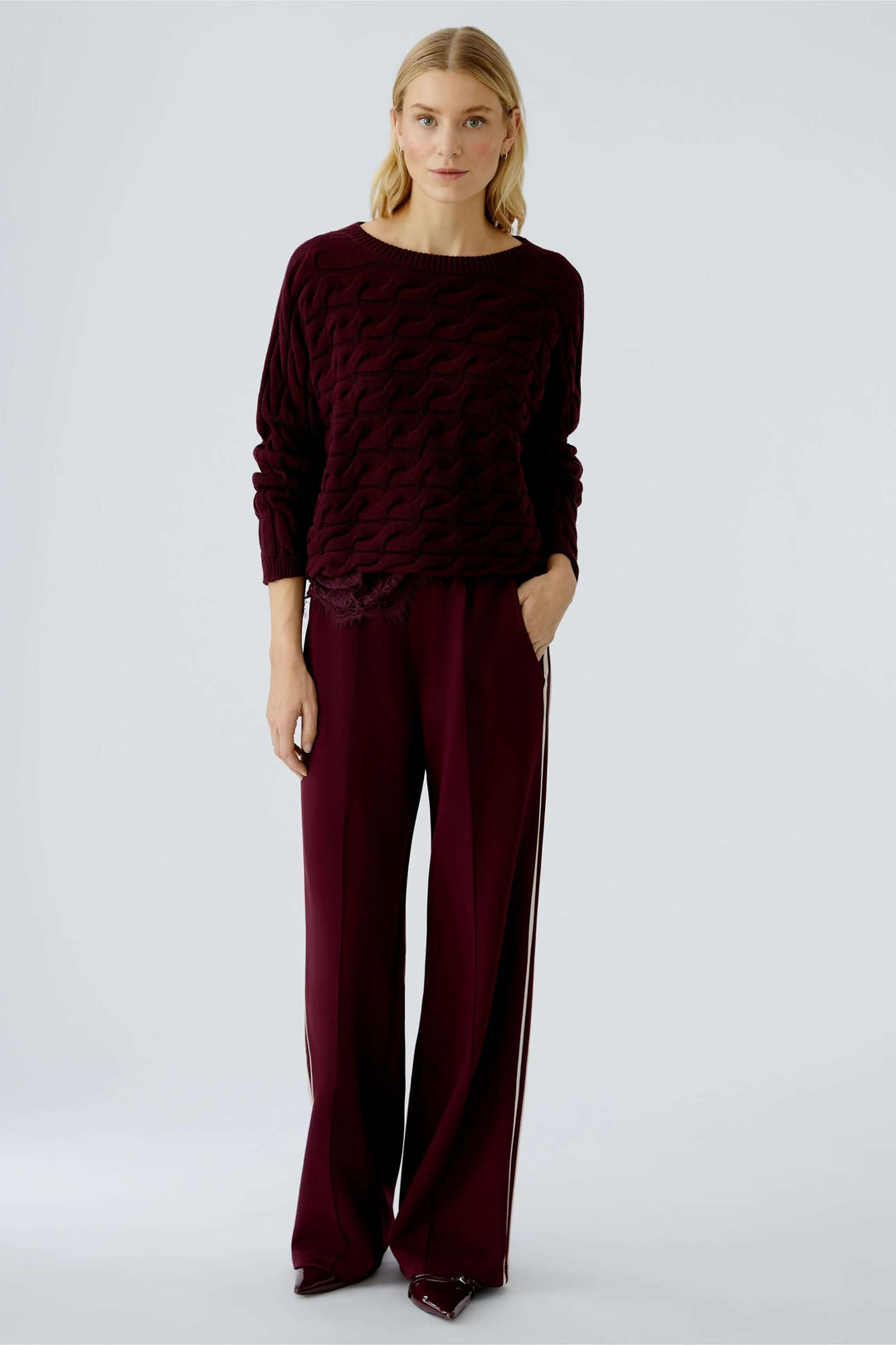 Femme portant un Tricot Sirah à col bateau moderne et élégant avec un motif torsadé et coupe carrée en coton doux.