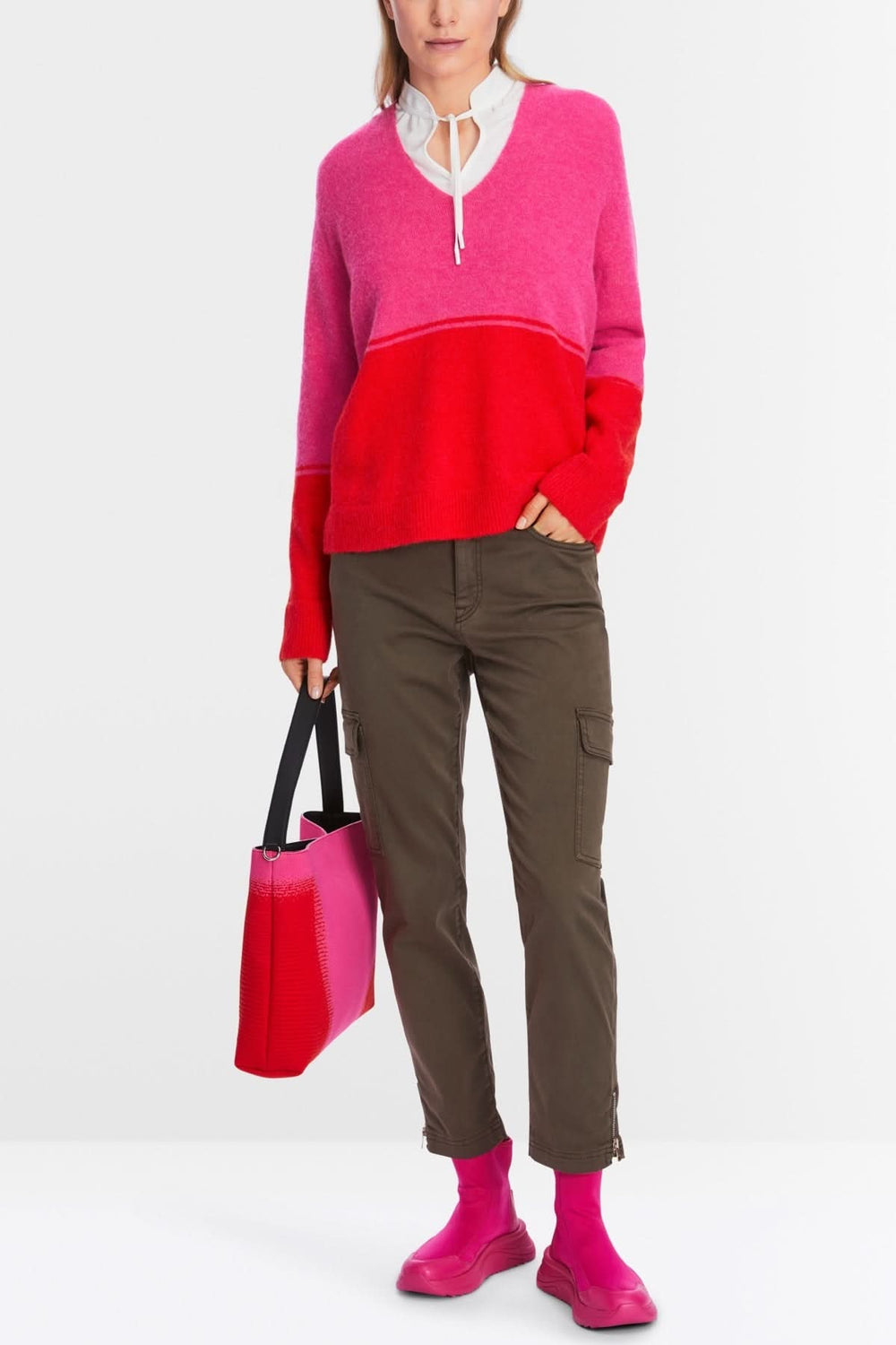 Tricot bicolore rouge et rose, encolure en V, porté avec un pantalon cargo et des chaussettes roses.