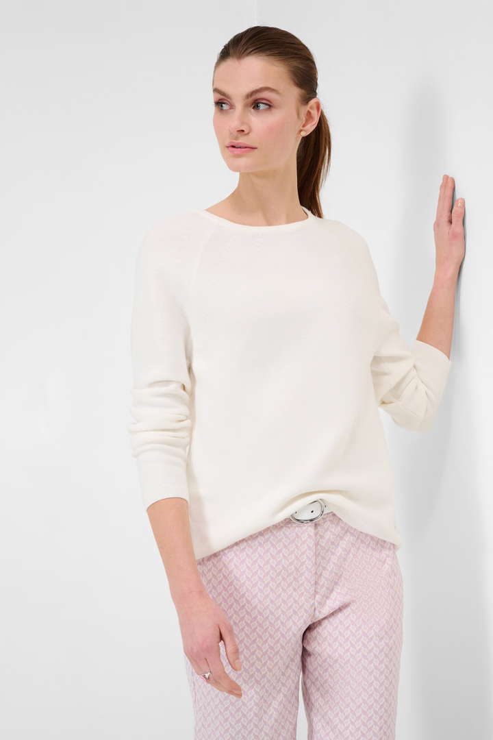 Femme portant un tricot col rond Lesley en blanc, stylé avec un pantalon rose chic.