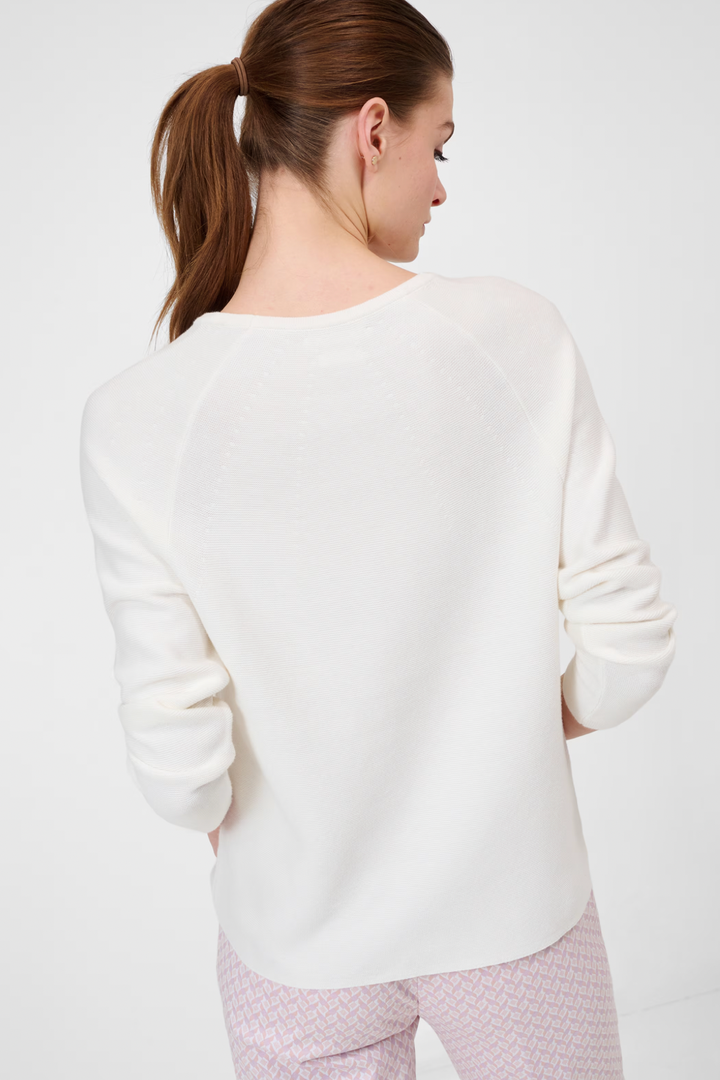 Femme portant un tricot col rond Lesley en blanc, vue de dos, avec pantalons décontractés.