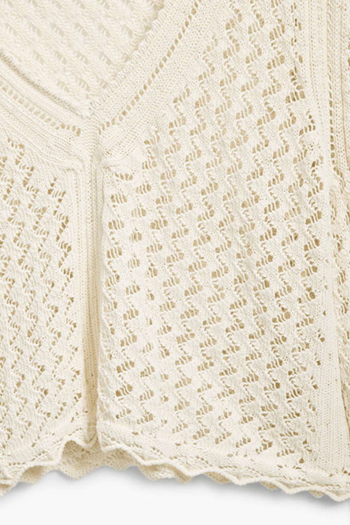 Tricot à motif ondulé en tissu ajouré, coloris crème, avec encolure en V et finitions délicates.