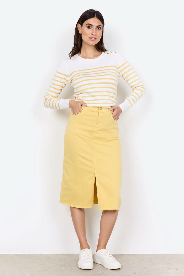 Femme portant un tricot rayé à encolure ronde et jupe jaune, look élégant et décontracté.