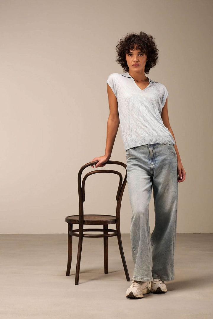 Femme en veste légère à col V, posant avec un pantalon en denim, style décontracté.