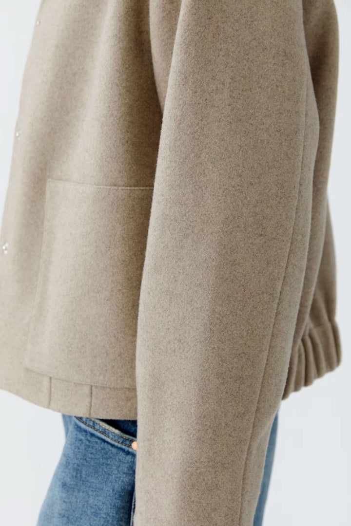 Veste à coupe droite en matière douce avec col classique et fermeture à boutons-pression, vue latérale sur mannequin en jean.