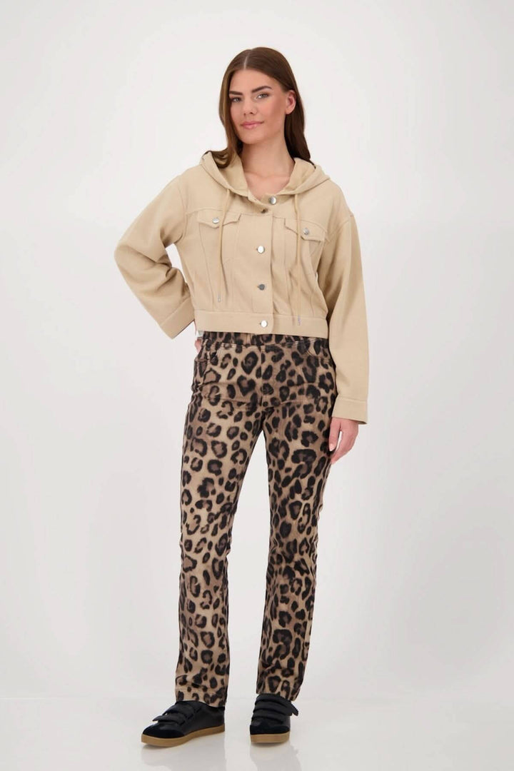 Femme portant une veste courte à capuchon beige avec un pantalon à imprimé léopard, style décontracté et moderne.