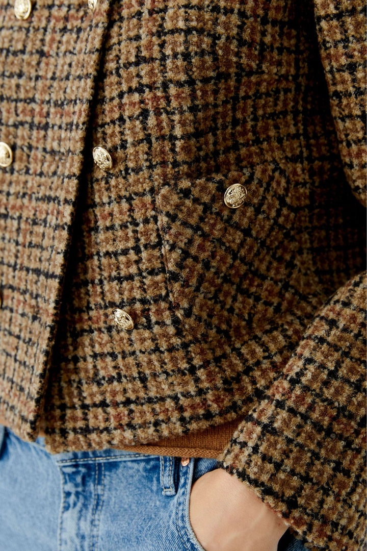 Veste courte à carreaux, boutons dorés en lainage texturé, portée avec un jean moderne pour un look élégant et actuel.