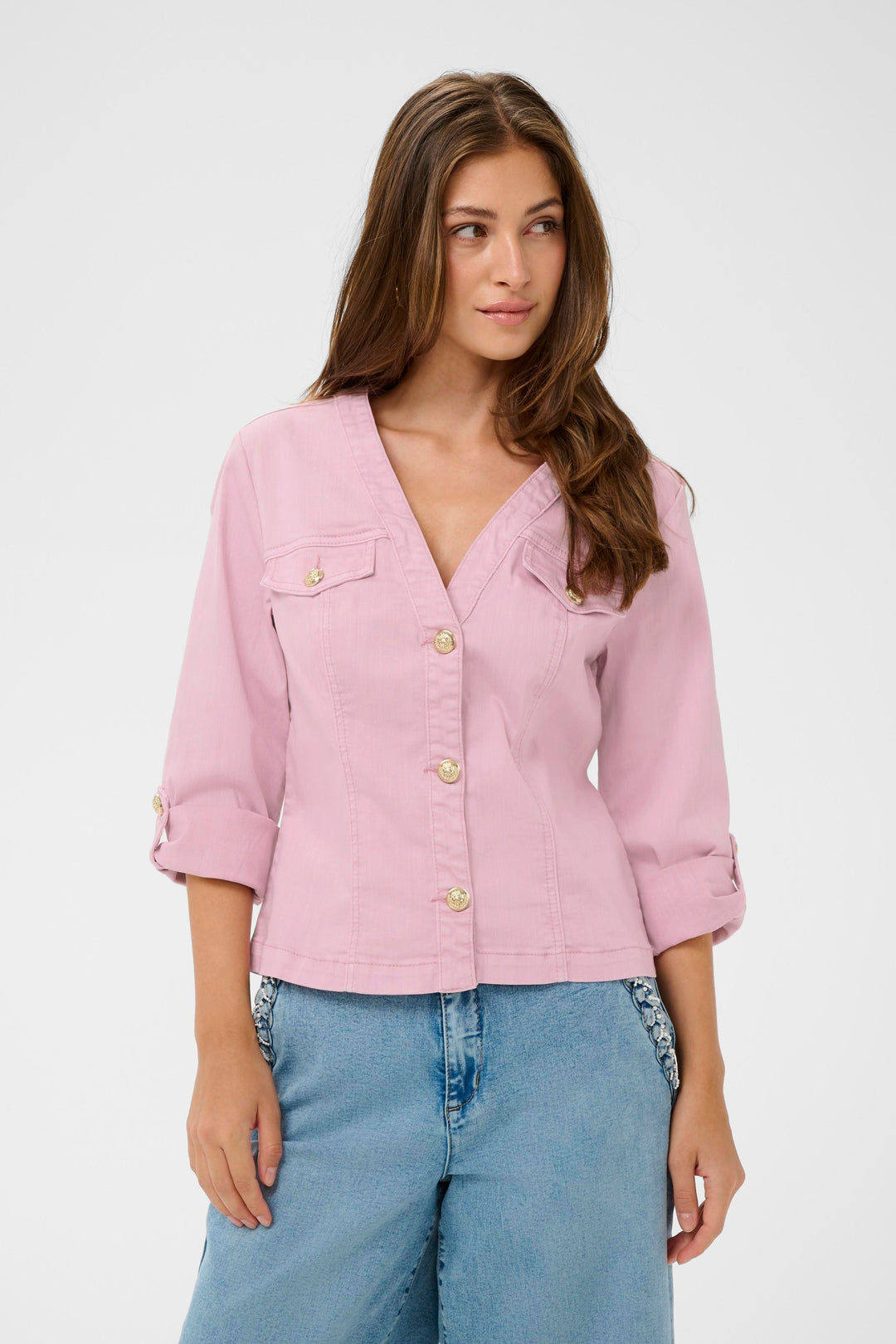 Femme portant la Veste en jean Visti rose, coupe ajustée avec boutons décoratifs, tenue moderne et féminine.