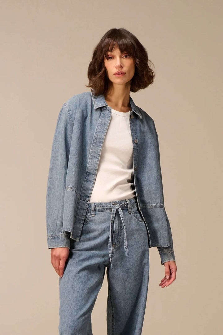 Veste en jean à manches longues avec denim souple, portée sur un t-shirt blanc pour un look décontracté et moderne.