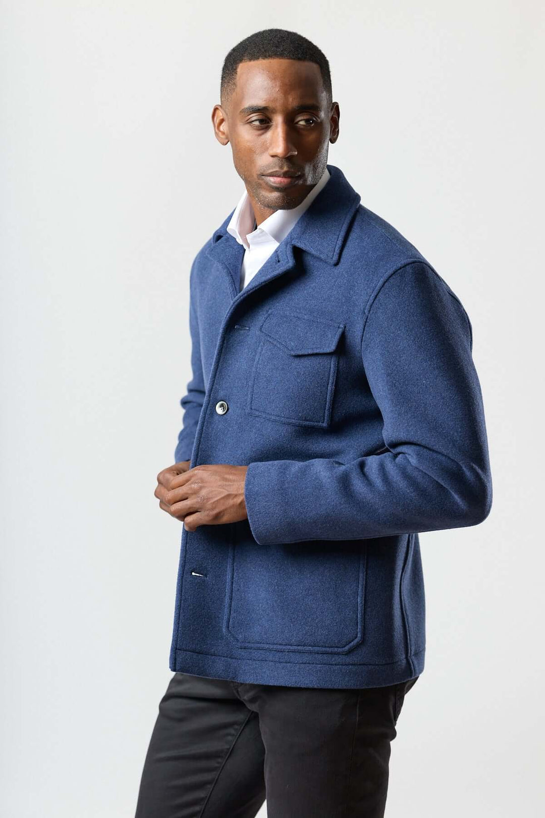 Homme portant une veste en laine à poches plaquées, bleu, style workwear, avec chemise blanche et pantalon foncé.
