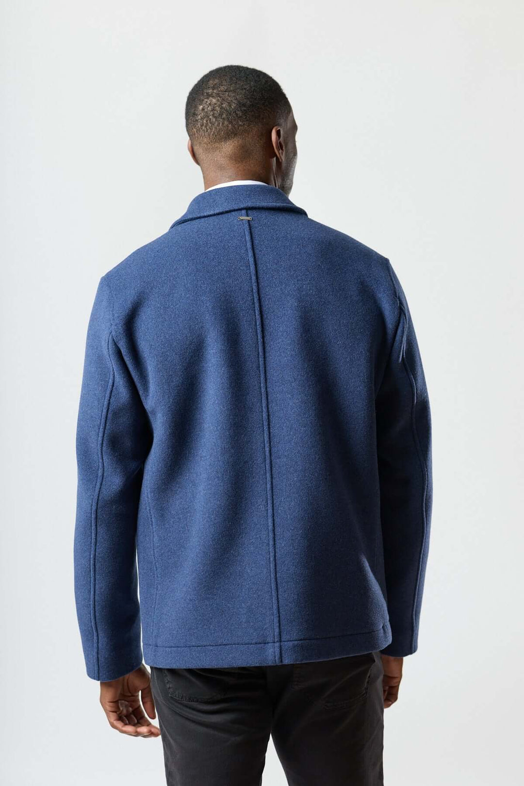 Homme portant une veste en laine à poches plaquées bleue vue de dos, montrant la coupe droite et la texture douce du tissu.