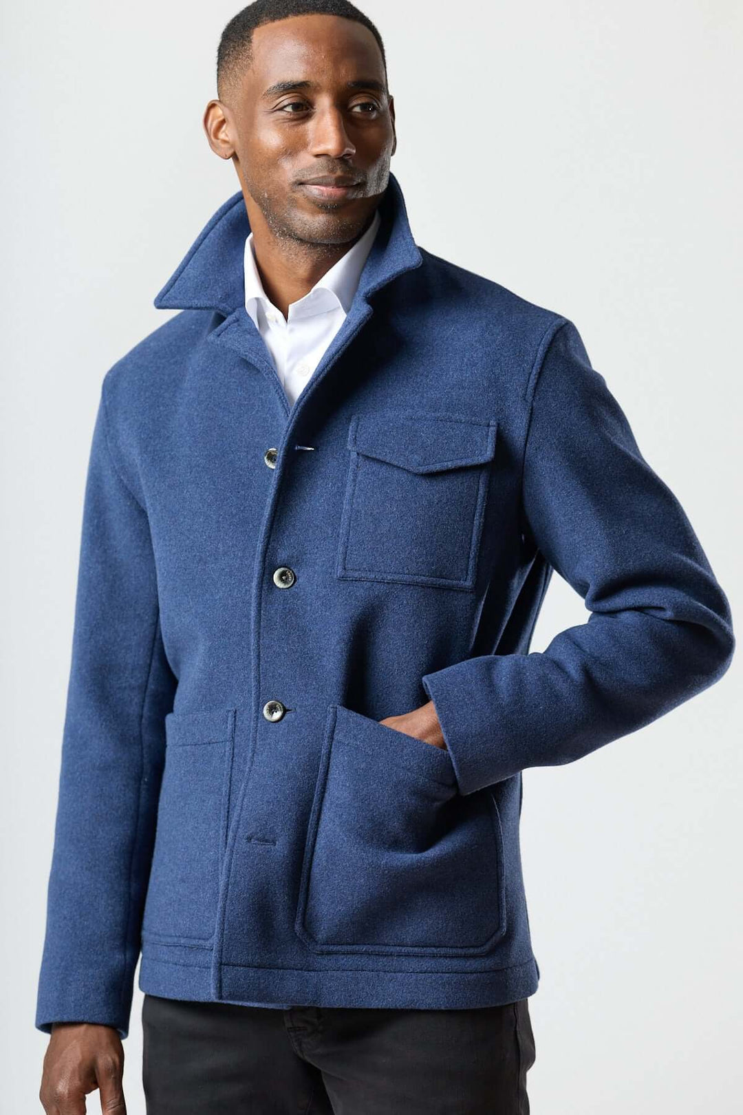 Homme portant une veste en laine à poches plaquées bleu, style workwear, sur une chemise blanche.