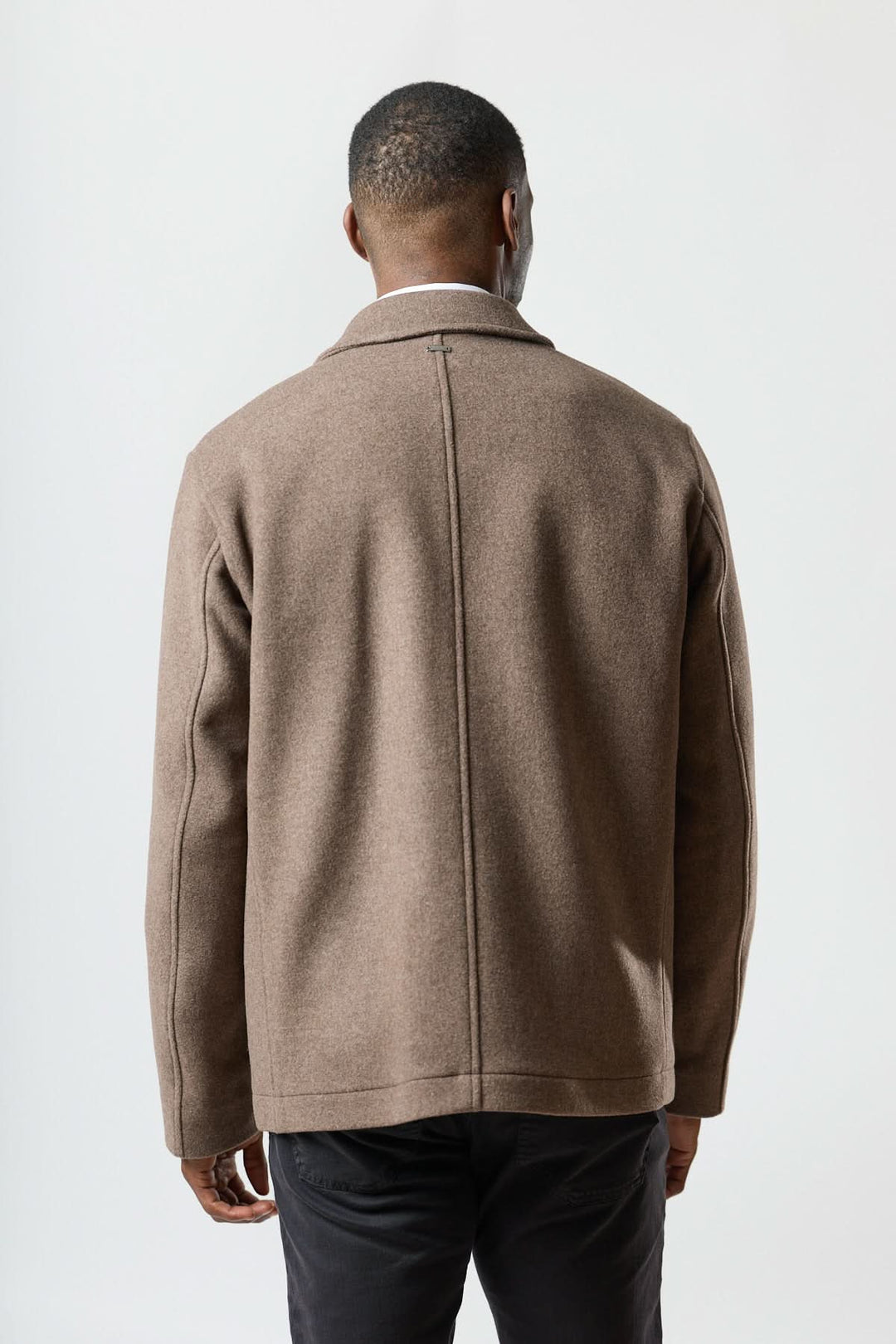 Homme portant une veste en laine à poches plaquées, coupe droite et élégante, vu de dos pour un style chic et polyvalent.