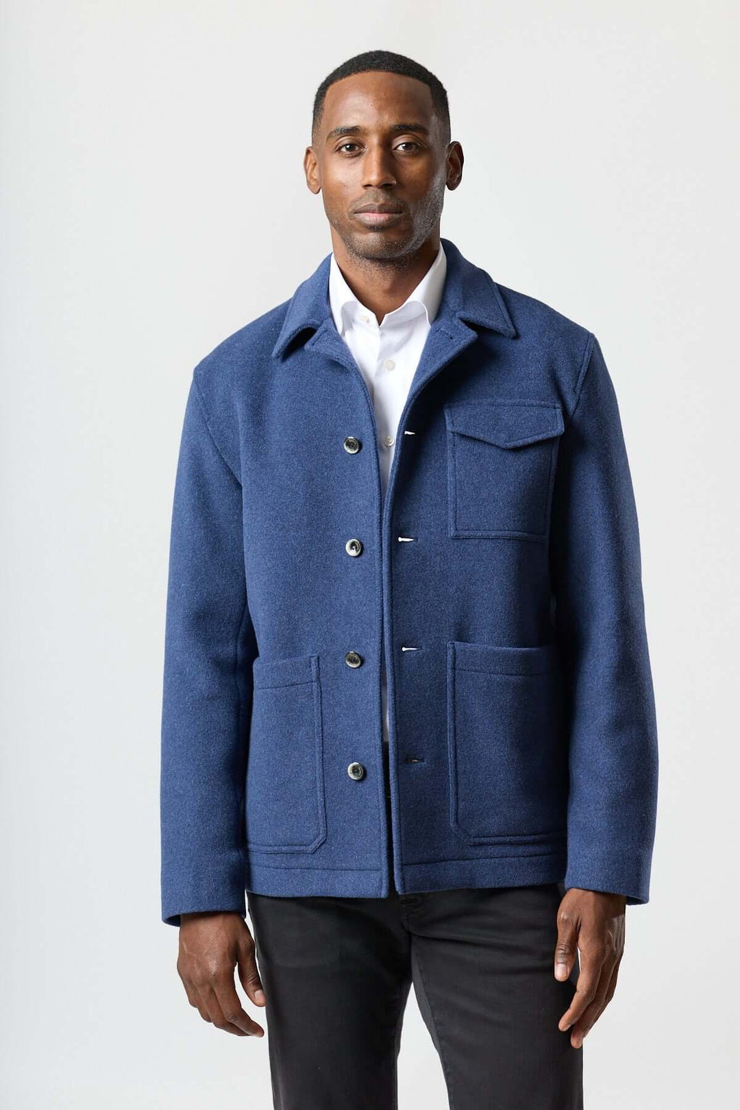 Homme portant une veste en laine à poches plaquées bleue, style workwear, idéale pour superpositions élégantes et structurées.