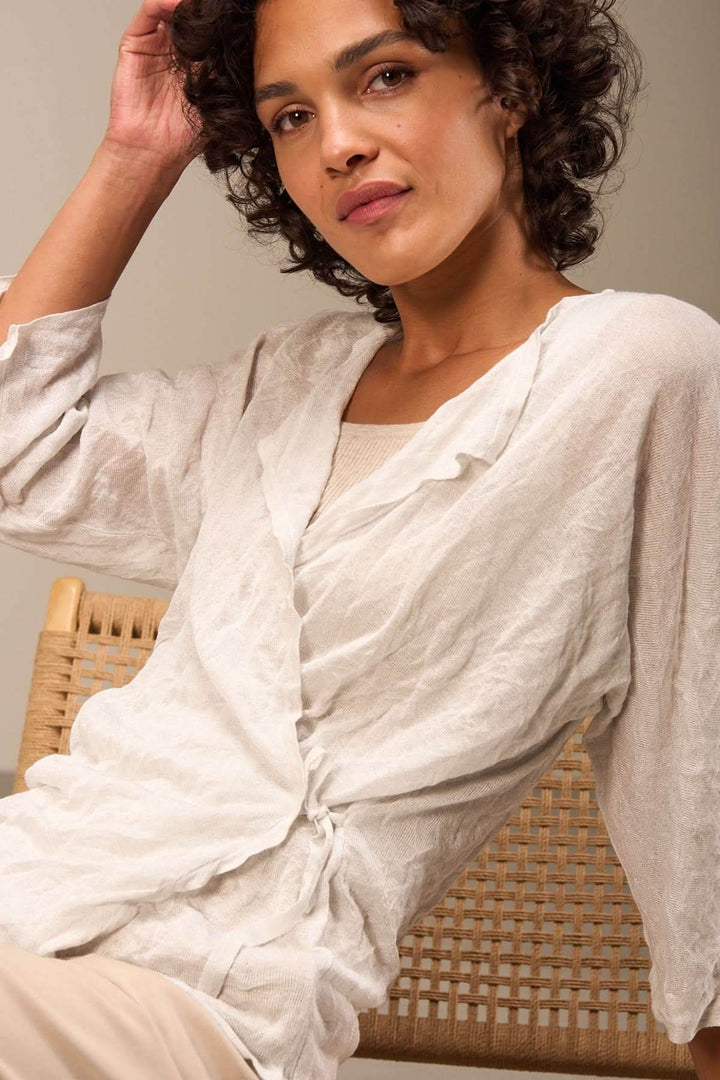 Veste en tissu léger et texturé, blanche, avec manches trois-quarts et lien à nouer à l'avant, sur modèle, style chic.