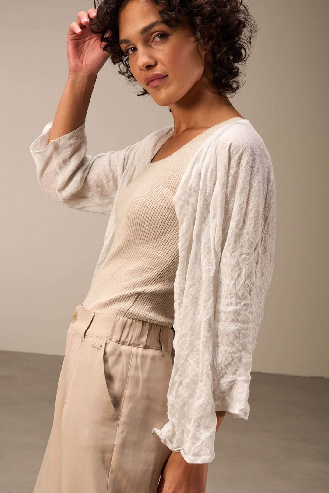 Femme portant une veste en tissu léger blanche avec des manches trois-quarts, style décontracté et élégant.
