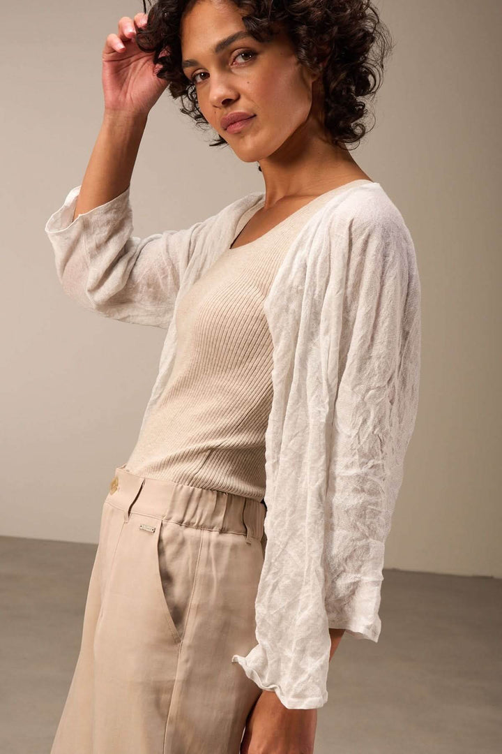 Femme portant une veste en tissu léger blanche avec des manches trois-quarts, style décontracté et élégant.