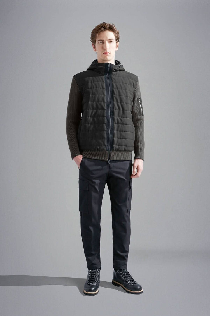 Homme portant une veste imperméable à capuchon, matelassée à l'avant et confortable, avec pantalon noir.