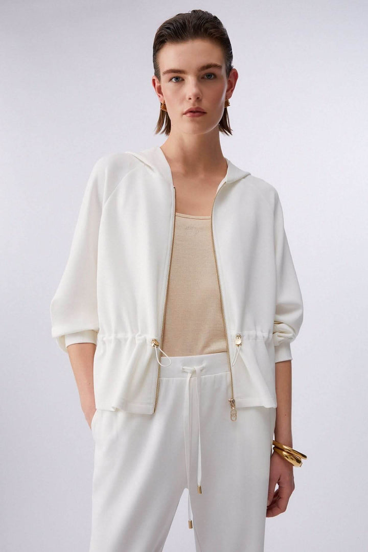 Femme portant une veste légère à capuchon avec cordon ajustable et fermeture à glissière, tenue idéale pour une allure moderne et décontractée.