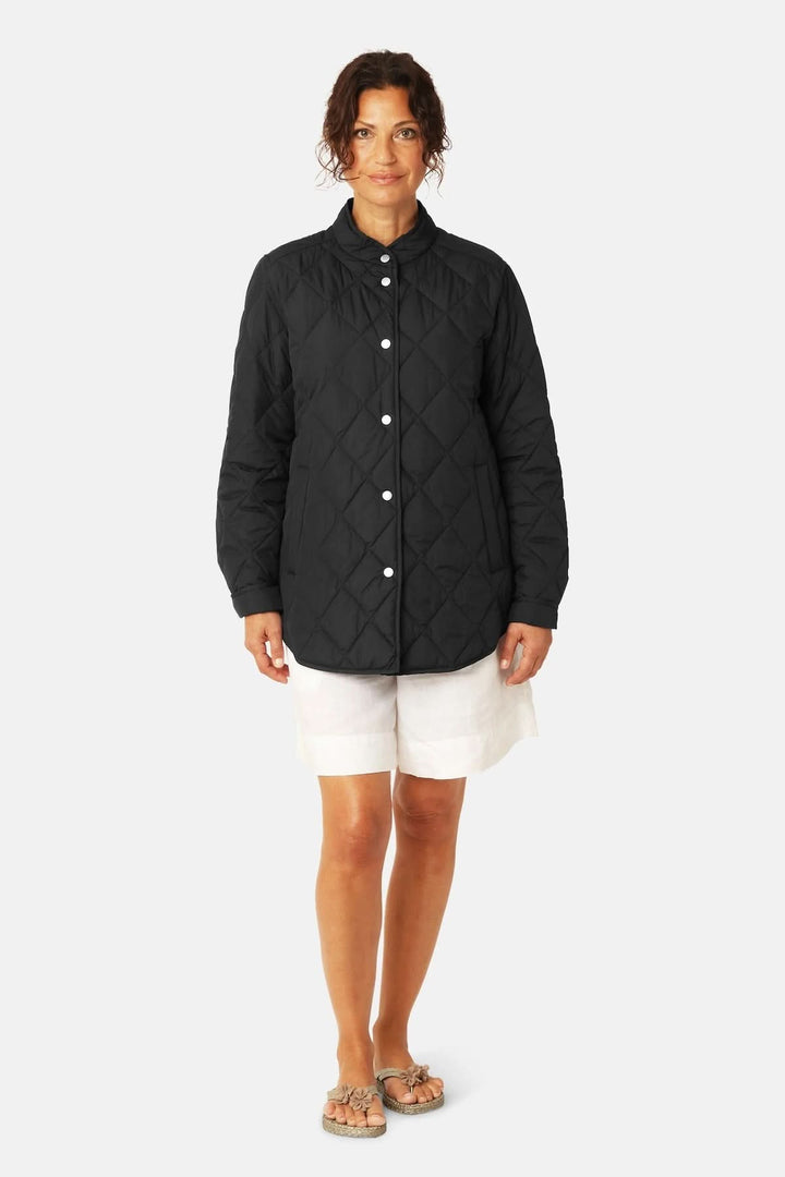 Veste matelassée légère à col montant noire portée par une femme, offrant style intemporel et protection contre le vent.