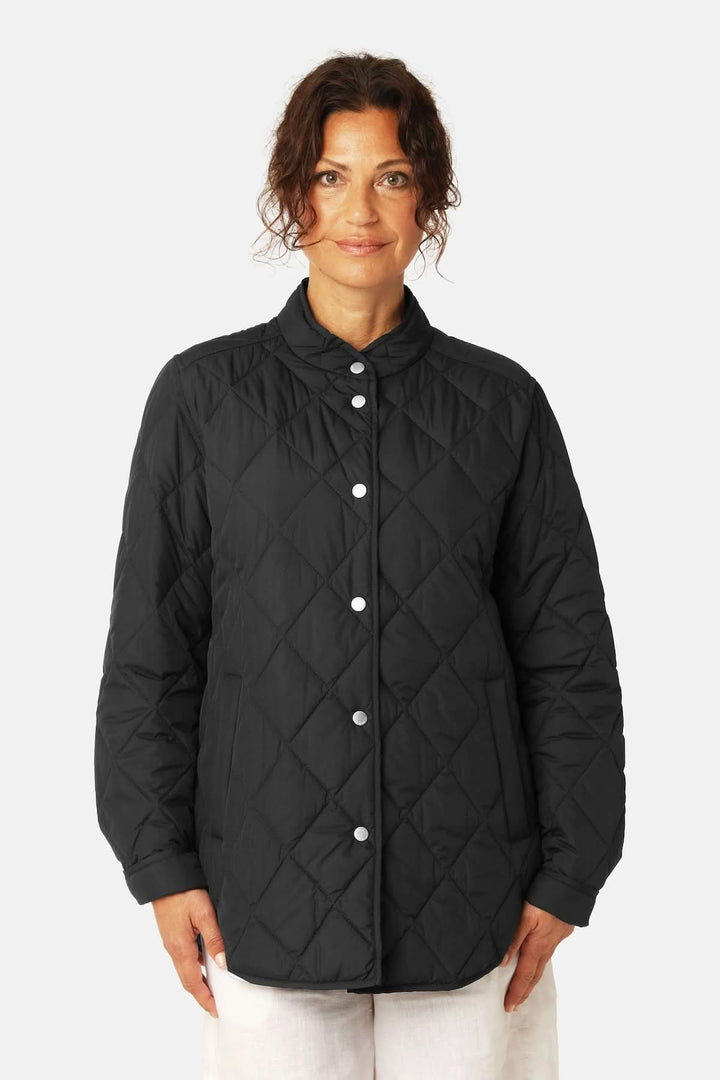 Veste matelassée légère à col montant, style intemporel avec piquage en losanges, idéal pour la mi-saison. Femme souriante portant la veste.