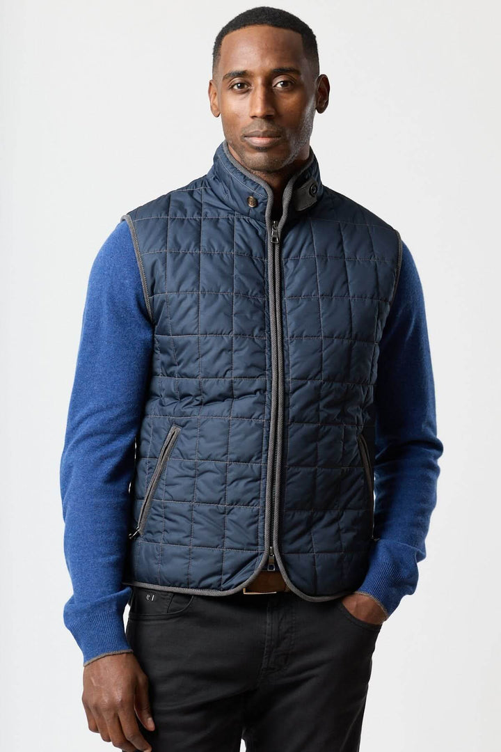 Homme portant une veste sans manches matelassée avec détails en velours côtelé, style élégant et pratique.