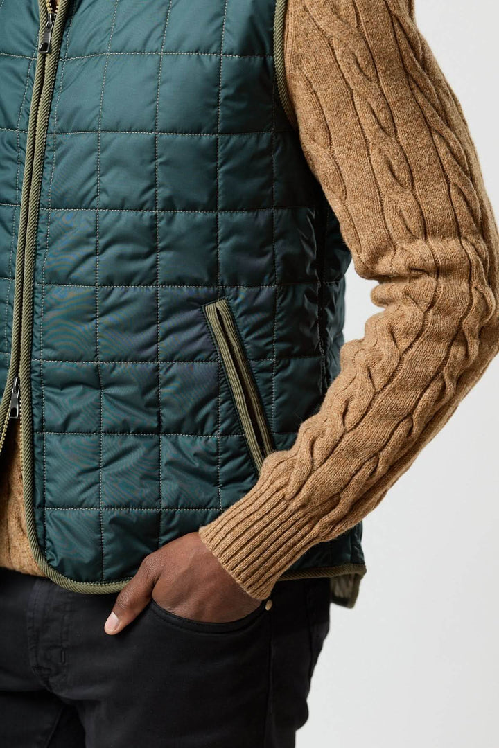 Veste sans manches matelassée avec détails en velours côtelé portée sur un chandail tricoté beige, vue de côté.