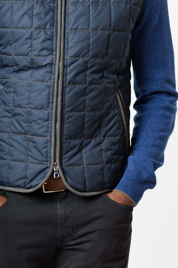 Homme portant une veste sans manches matelassée avec détails en velours côtelé, ajoutant une touche de style raffiné et élégant.