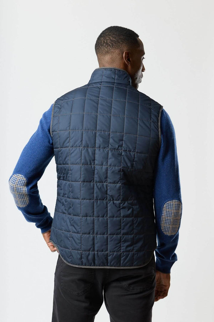 Homme portant une veste sans manches matelassée avec détails en velours côtelé, vue de dos, accentuant le style et l&