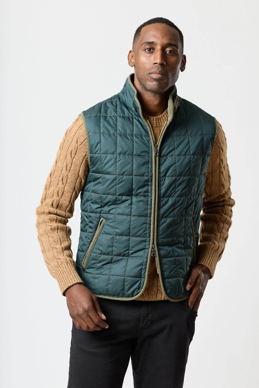 Veste sans manches matelassée avec détails en velours côtelé portée par un homme sur un pull beige, élégante et texturée.
