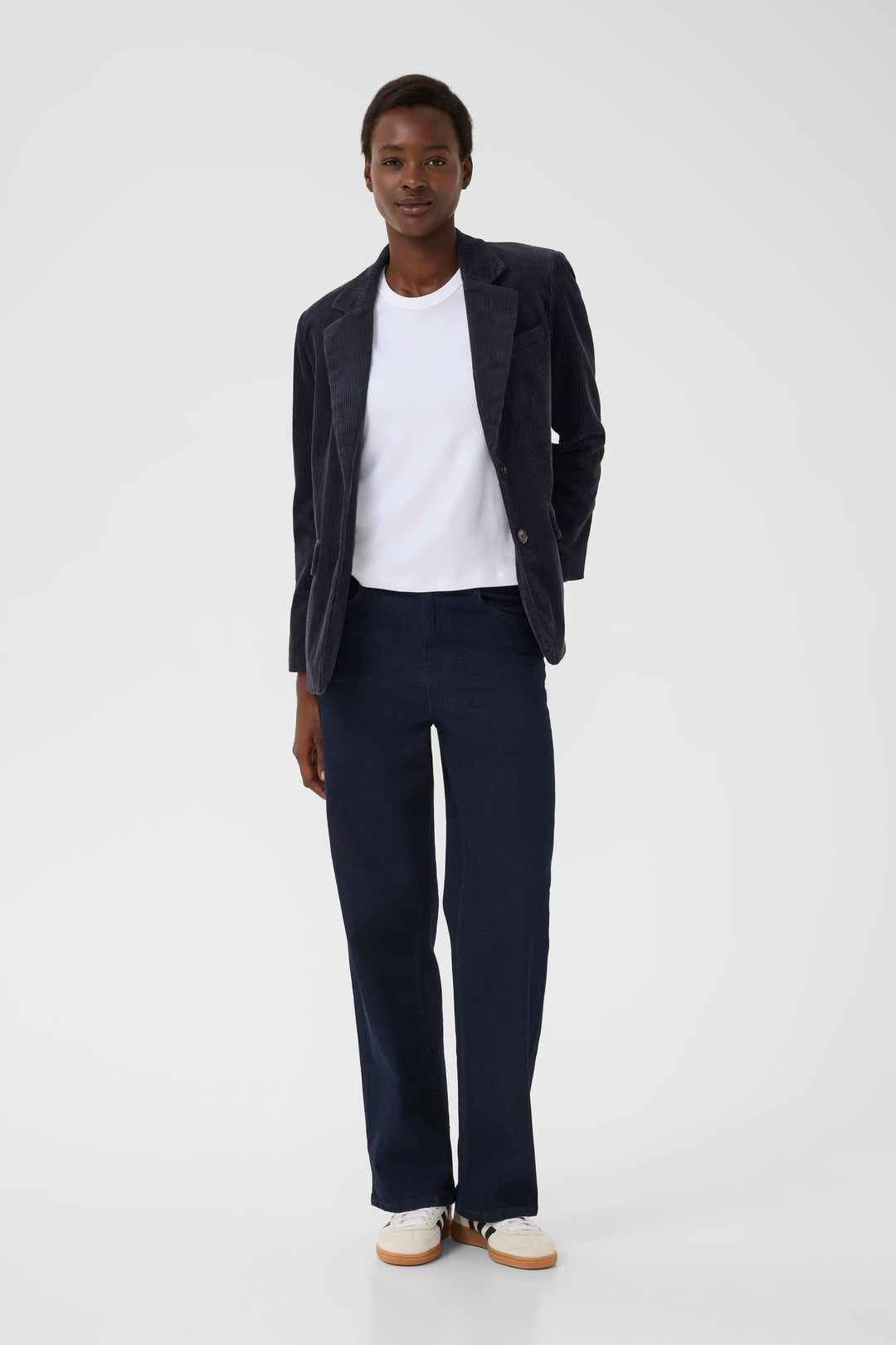 Veston Leni en velours côtelé, coupe ajustée, porté avec un t-shirt blanc et un pantalon bleu foncé.