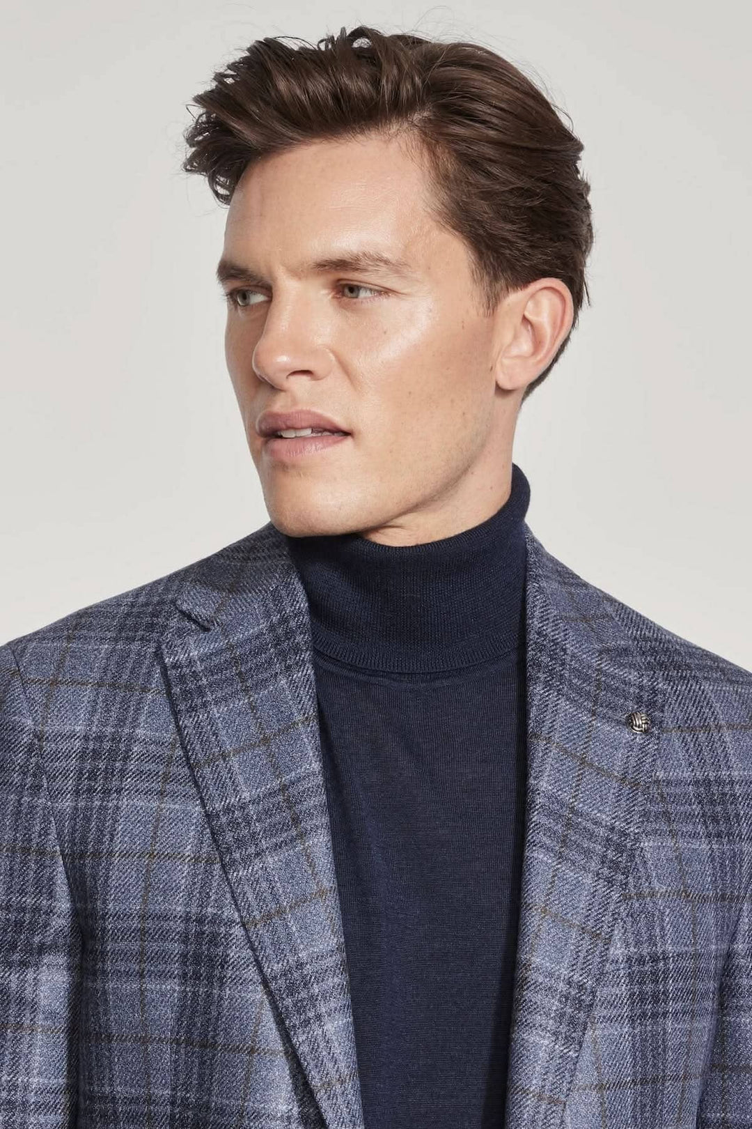 Homme portant une veste à carreaux en laine et soie avec un col roulé noir, affichant un look élégant.
