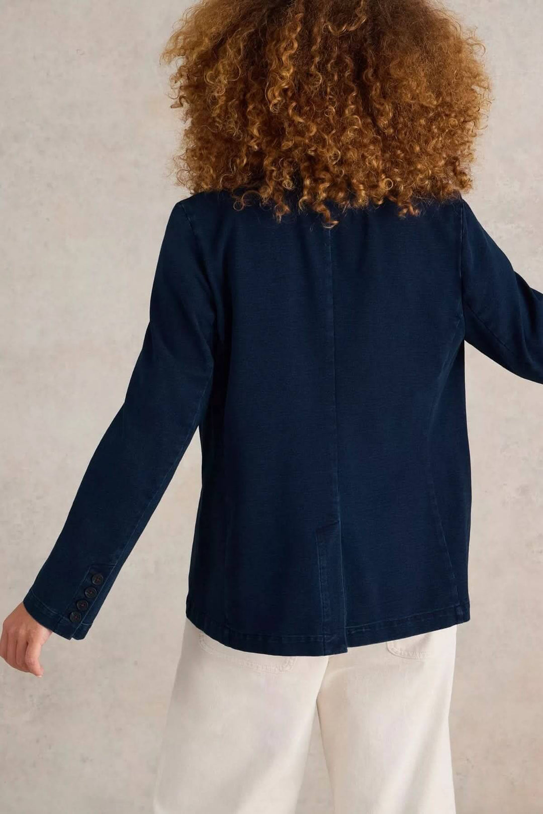 Veston décontracté en denim bleu foncé, coupe droite, porté par une femme, dos visible. Style moderne et polyvalent.