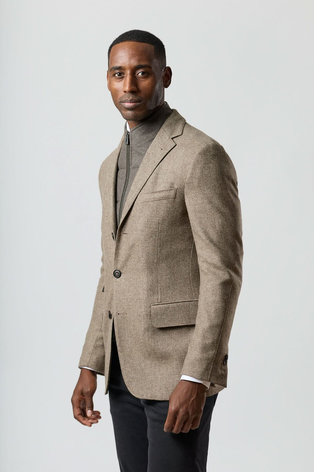 Homme portant un veston texturé en laine avec col amovible intégré en beige doré, allure élégante et contemporaine.