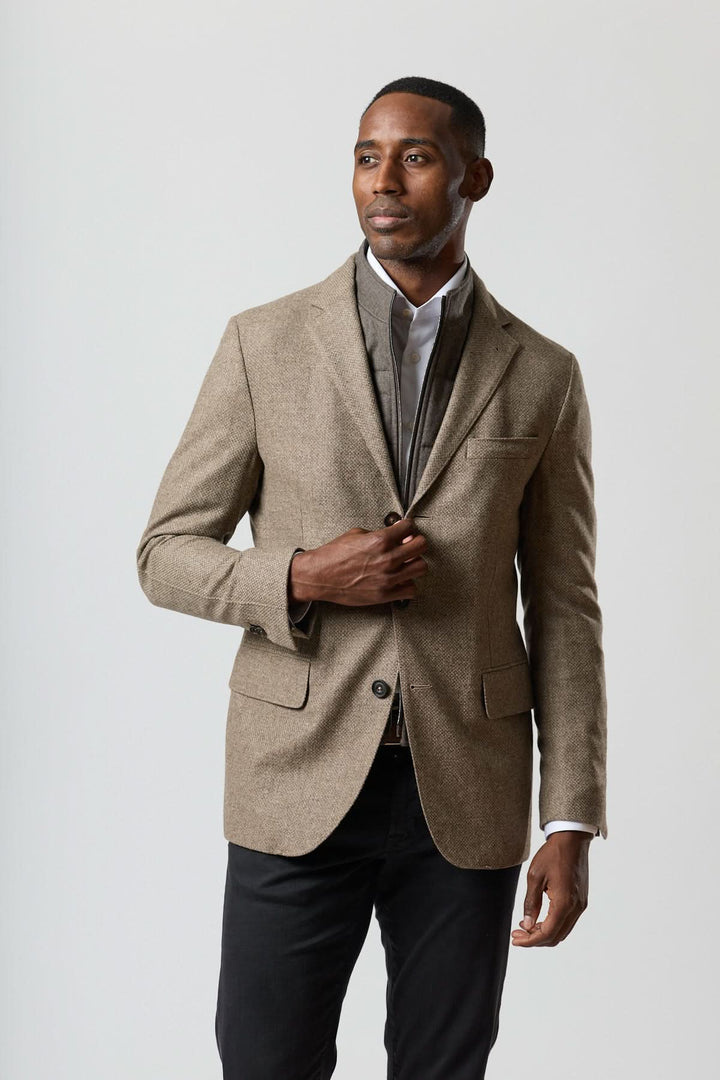 Veston texturé en laine avec col amovible intégré, tons beige doré, élégance moderne avec insert zippé, homme debout.