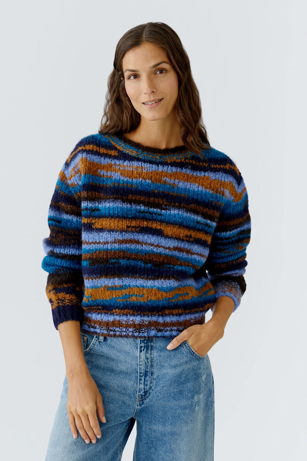 Femme portant un chandail en tricot rayé à col rond, texture moelleuse, rayures multicolores pour un look cosy, idéal pour l'hiver.