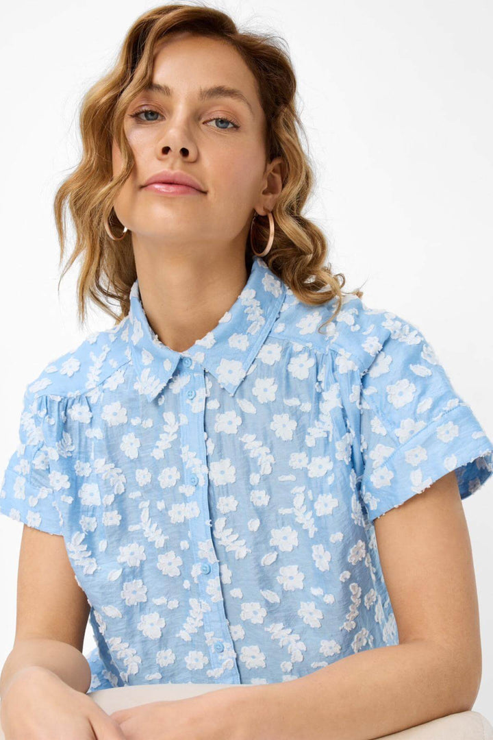 Blouse VIV broderie florale à motifs floraux délicats sur fond bleu, style oversize, idéale pour l'été.