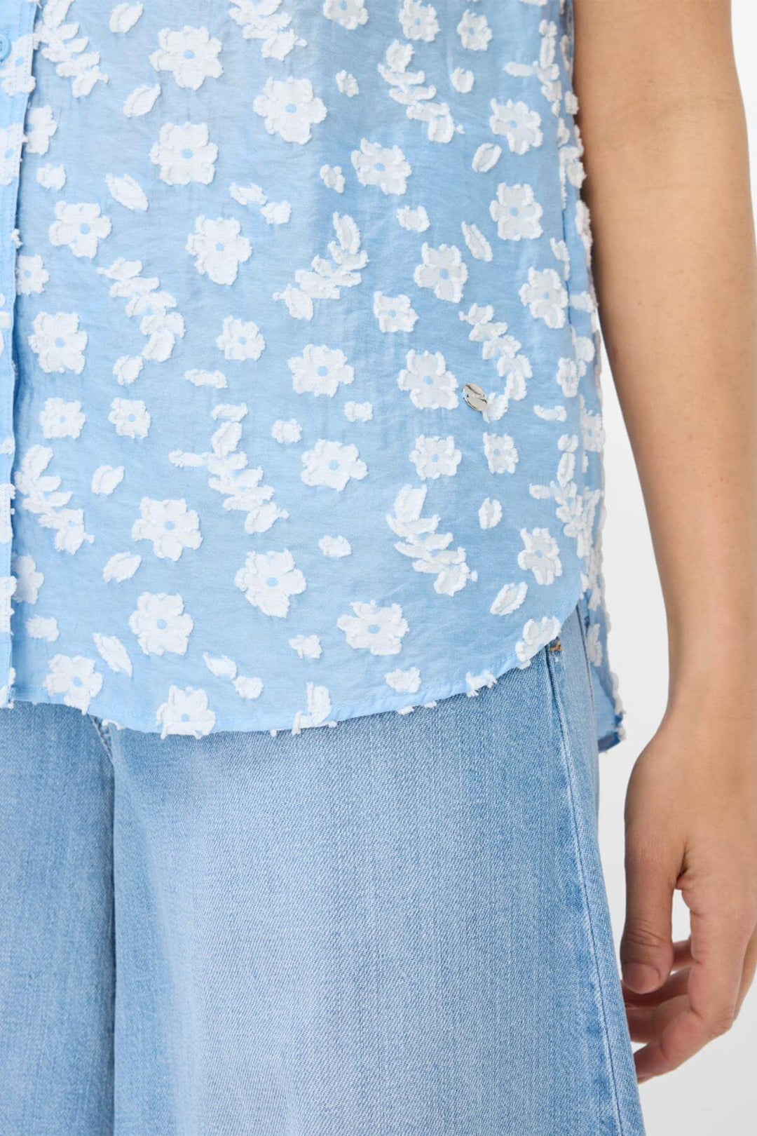 Blouse VIV en tissu léger bleu avec motifs floraux blancs et détails élégants pour une tenue d'été confortable.