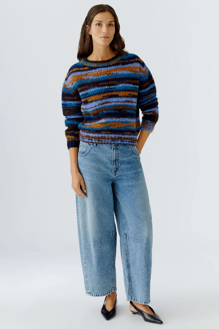 Femme portant un chandail en tricot rayé à col rond avec un jean, allure décontractée et cosy.
