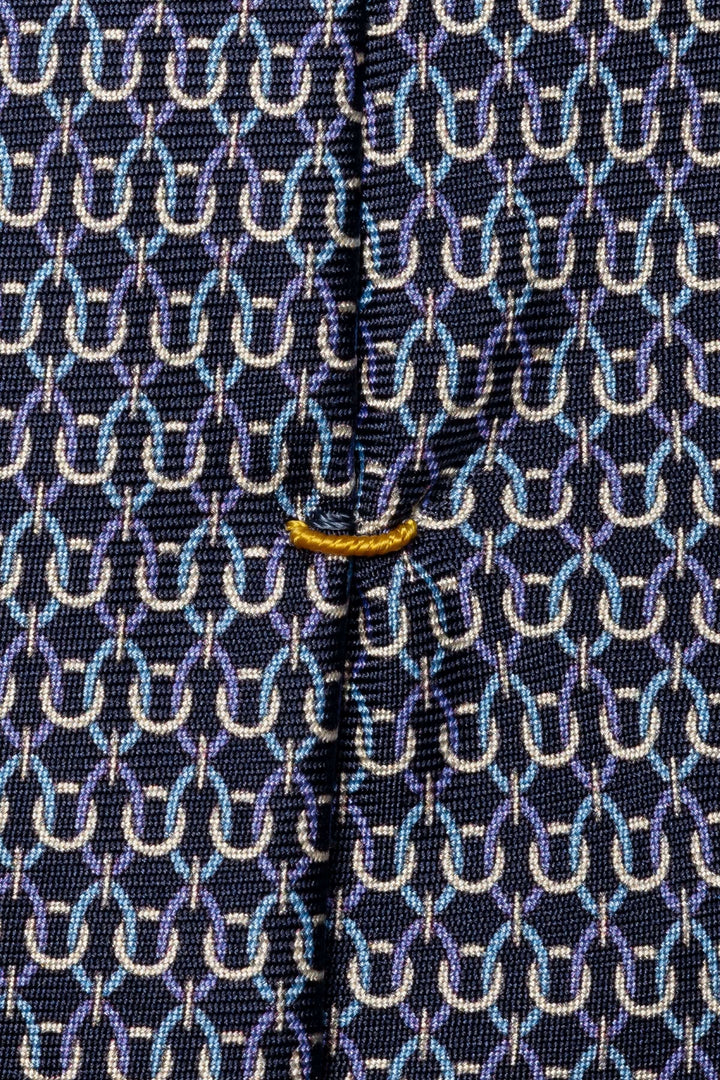 Cravate motif géométrique tissé en nuances de bleu et blanc sur fond foncé, avec finition soyeuse et détails raffinés.