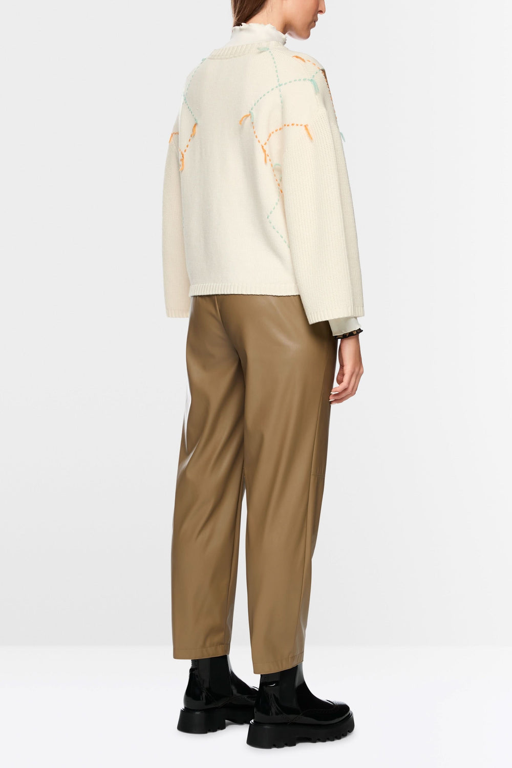 Dos d'un chandail à motif losanges et accents léopard avec pantalon en cuir marron et chaussures noires.