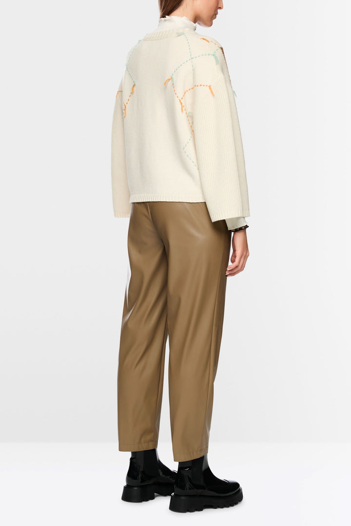 Dos d'un chandail à motif losanges et accents léopard avec pantalon en cuir marron et chaussures noires.