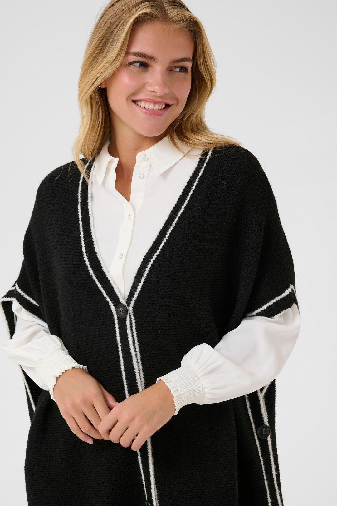 Femme portant une Cape Rams boutonnée en tricot à bord contrastant, chic et décontractée, parfaite pour superposer sur une chemise.