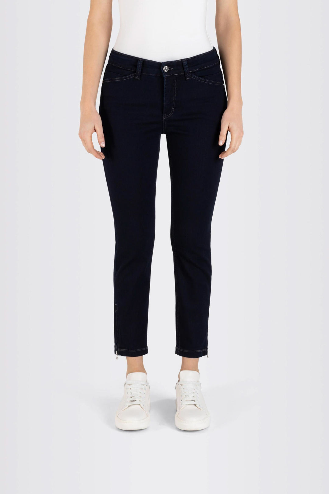 Jeans coupe ajustée longueur 7/8, tissu extensible, porté avec t-shirt et sneakers blancs.