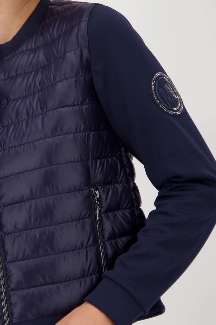 Veste matelassée bimatière à fermeture éclair avec manches souples et poche zippée, idéale pour look chic et sportif.