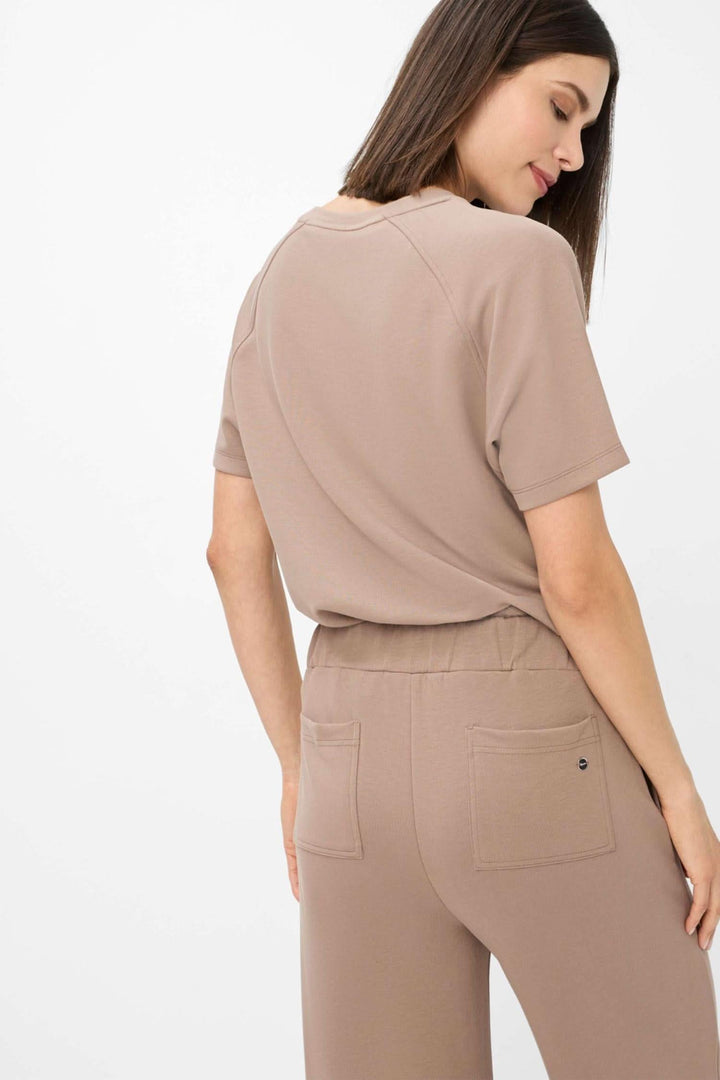 Femme portant un t-shirt beige assorti à un pantalon palazzo beige, vue arrière, style moderne et décontracté.