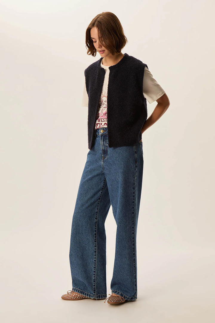 Alt Tag: Veste Achille sans manches en laine bouclée portée sur t-shirt imprimé et jean, style décontracté.
