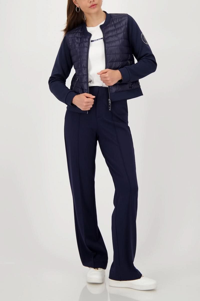 Femme portant une veste matelassée bimatière à fermeture éclair, style moderne et confortable, manches souples pour mouvement optimal.